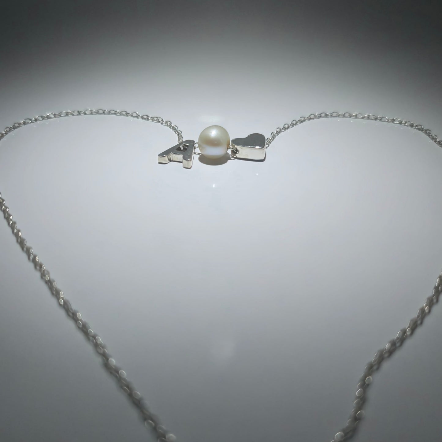 Sterling silver necklace with a pearl in between a silver heart and ANY LETTER