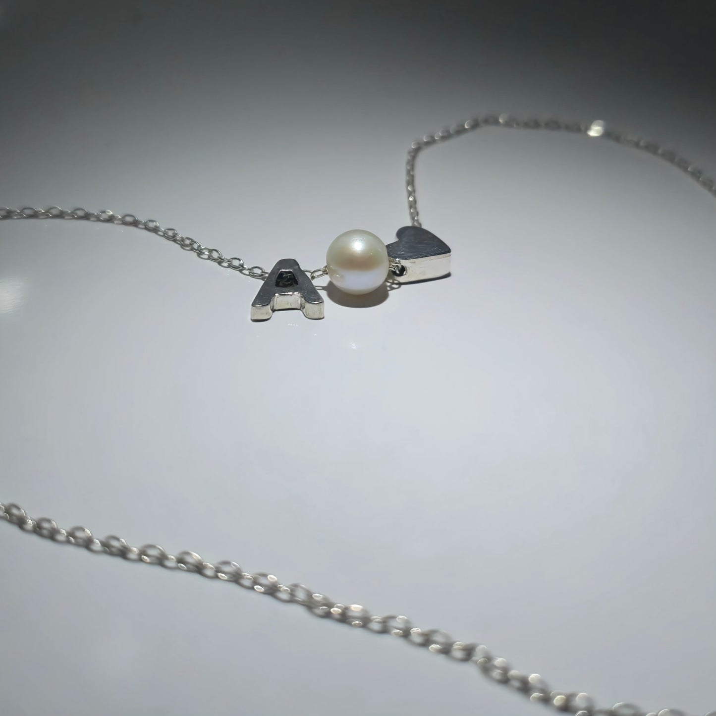 Sterling silver necklace with a pearl in between a silver heart and ANY LETTER